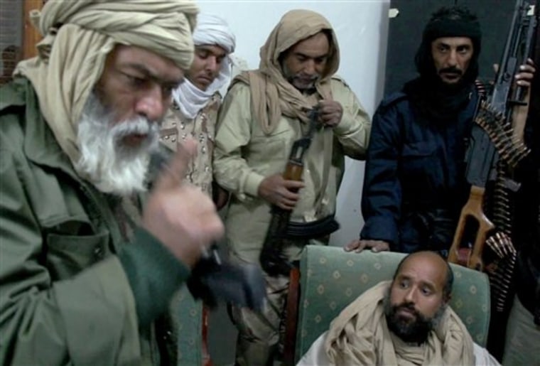 In an image taken from video, Moammar Gadhafi's son Seif al-Islam, below right, is surrounded by Libyan revolutionary captors shortly after his capture on Saturday, Nov. 19, 2011, at a safe house in the town of Zintan, Libya. 